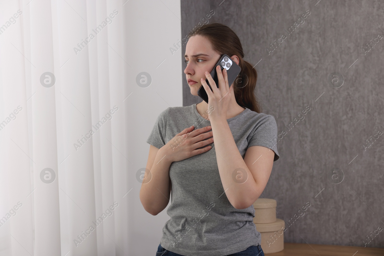 Photo of Stressed woman calling hotline for mental health help near window at home. Space for text