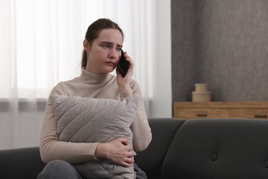 Photo of Depressed woman calling hotline for mental health help on sofa at home. Space for text