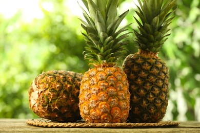 Photo of Fresh ripe pineapples on wooden table against blurred background