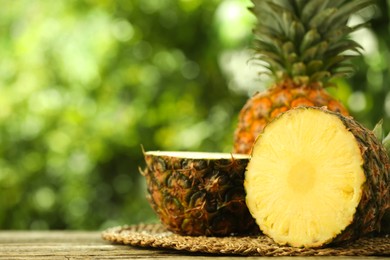 Photo of Fresh ripe pineapples on wooden table against blurred background, closeup. Space for text