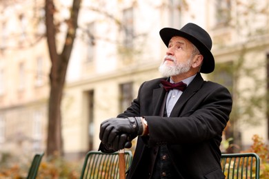 Photo of Elegant bearded man with walking cane on bench in park. Space for text