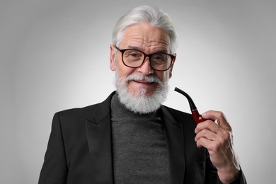 Photo of Senior man with tobacco pipe on light grey background