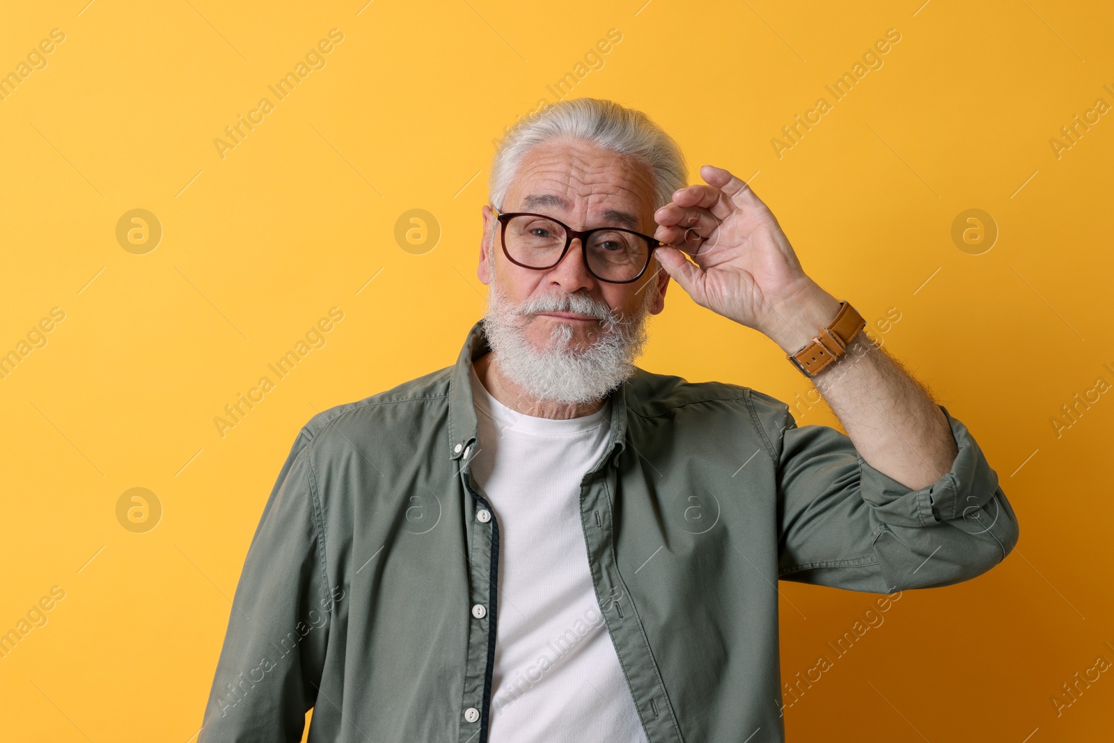 Photo of Portrait of senior man with gray beard on orange background