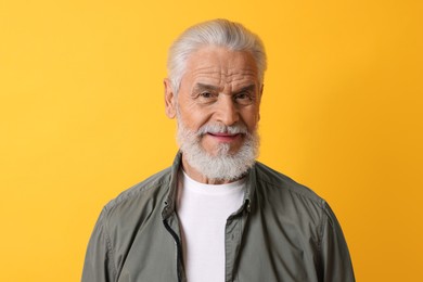 Photo of Portrait of senior man with gray beard on orange background