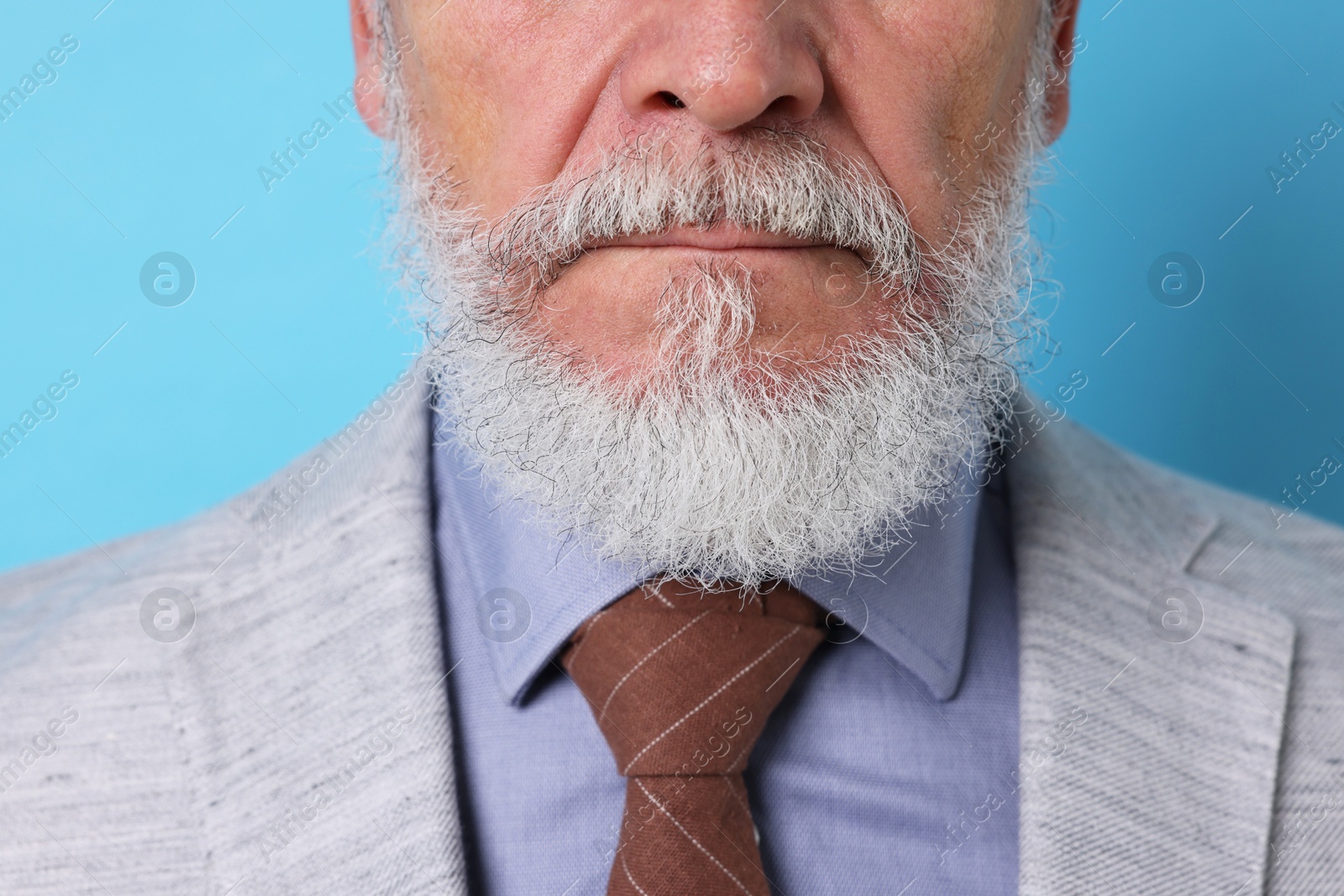 Photo of Senior man with gray beard on light blue background, closeup