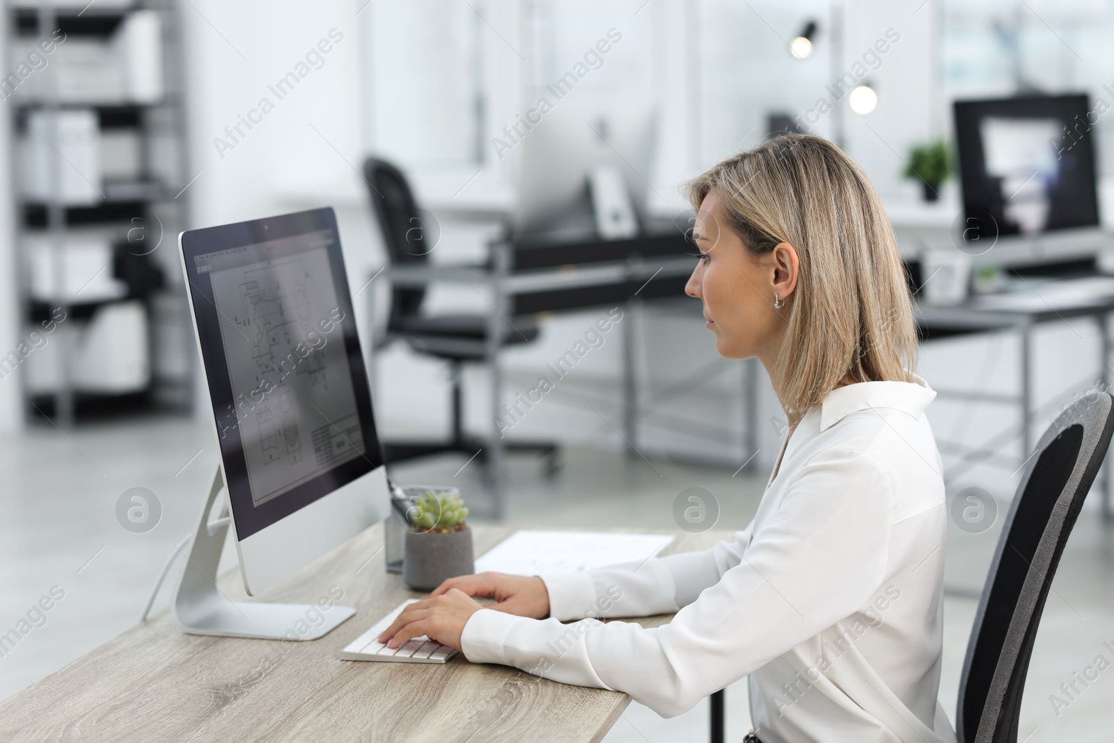 Photo of Technician making digital engineering drawing on computer at desk in office