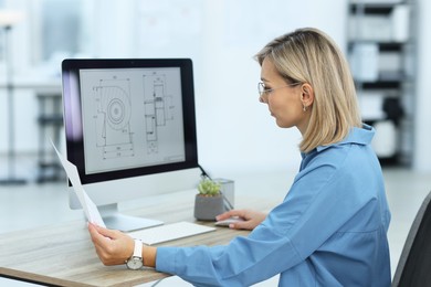 Photo of Technician making digital engineering drawing on computer at desk in office