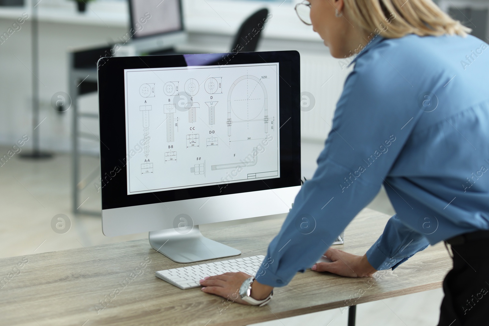 Photo of Technician making digital engineering drawing on computer at desk in office