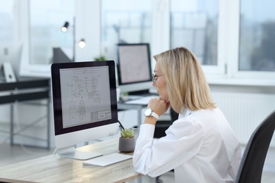 Photo of Technician making digital engineering drawing on computer at desk in office