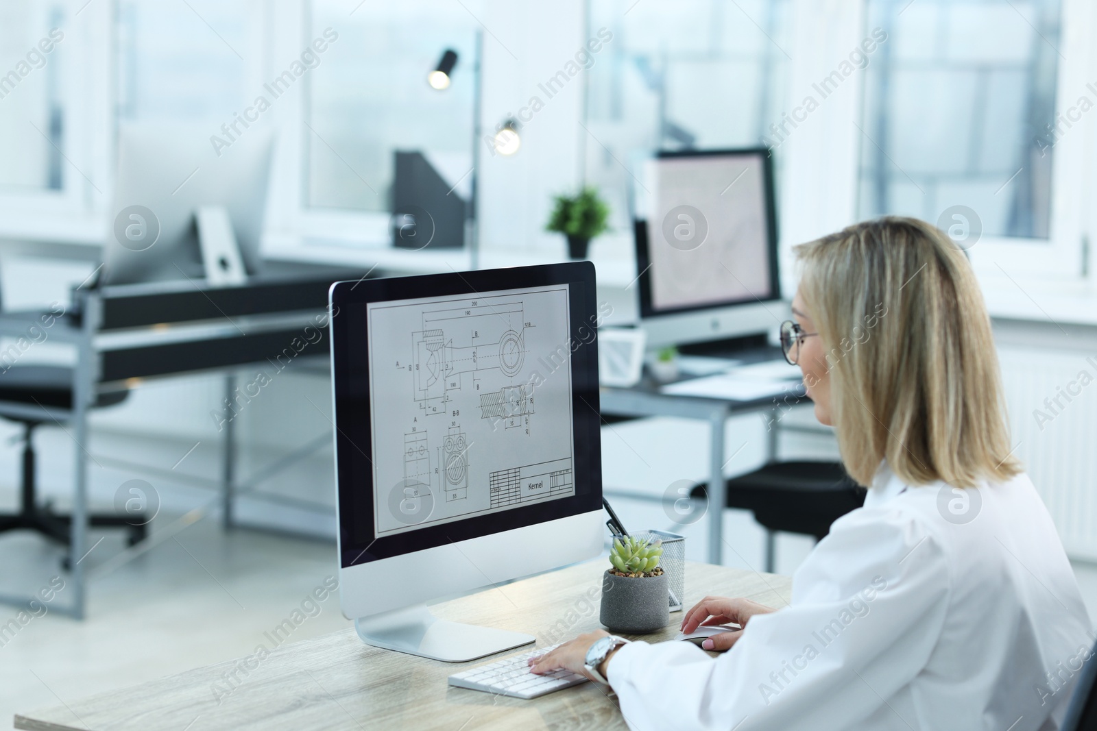 Photo of Technician making digital engineering drawing on computer at desk in office