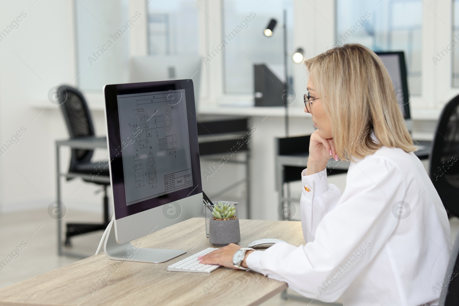 Photo of Technician making digital engineering drawing on computer at desk in office