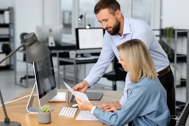 Photo of Technicians making digital engineering drawing on computer at desk in office