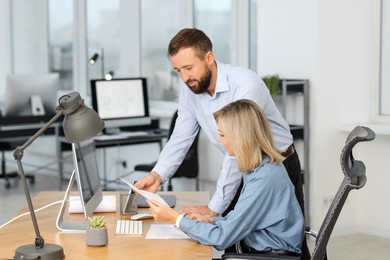 Photo of Technicians making digital engineering drawing on computer at desk in office