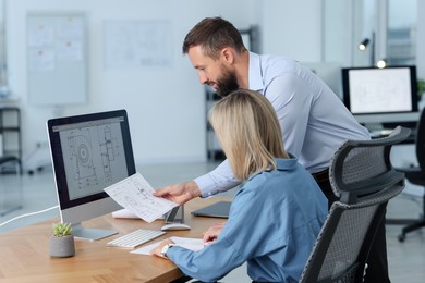 Photo of Technicians making digital engineering drawing on computer at desk in office