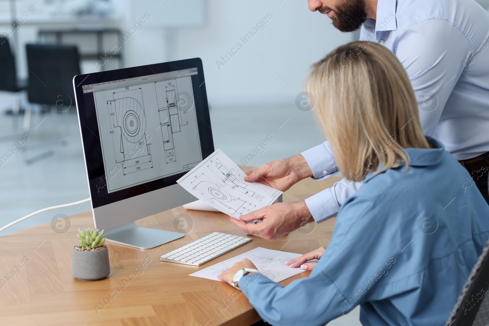 Photo of Technician making digital engineering drawing on computer at desk in office