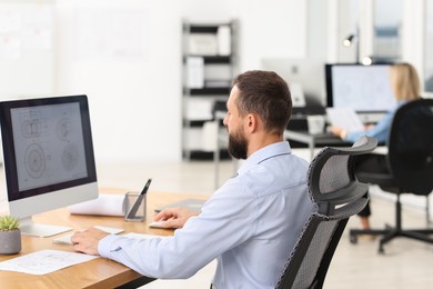 Photo of Technician making digital engineering drawing on computer at desk in office