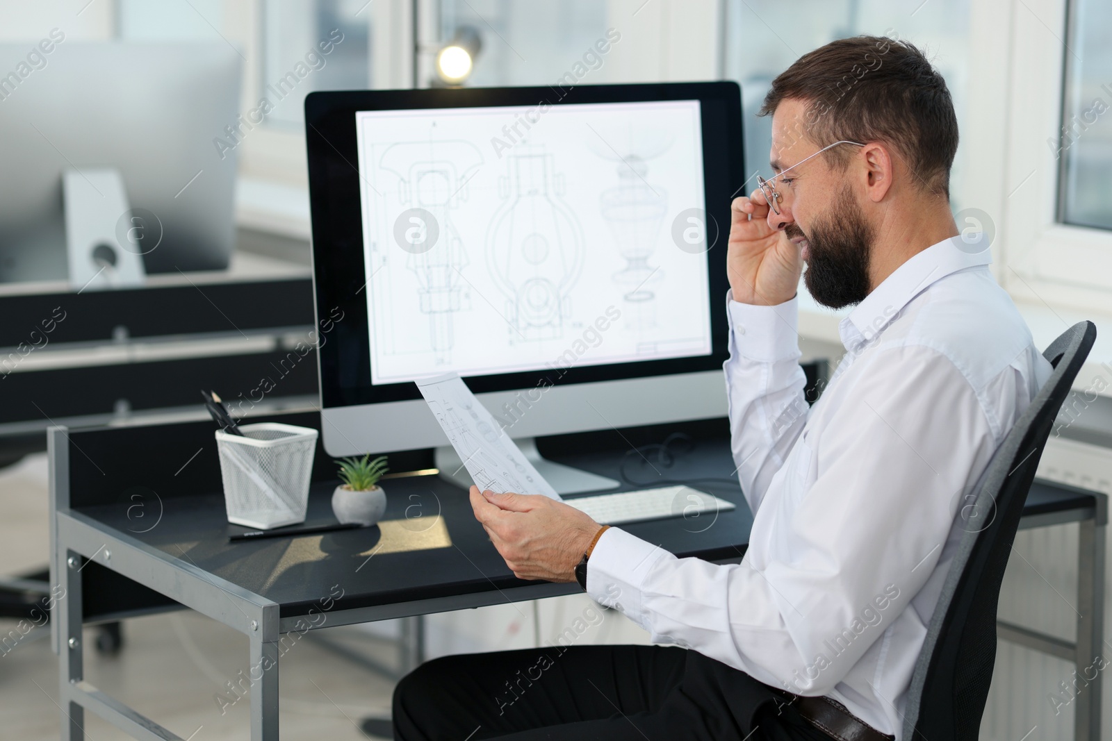 Photo of Technician making digital engineering drawing on computer at desk in office