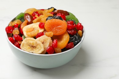 Photo of Mix of different dried fruits in bowl on white marble table, closeup