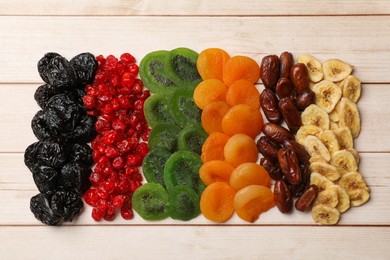 Photo of Mix of different dried fruits on wooden table, top view