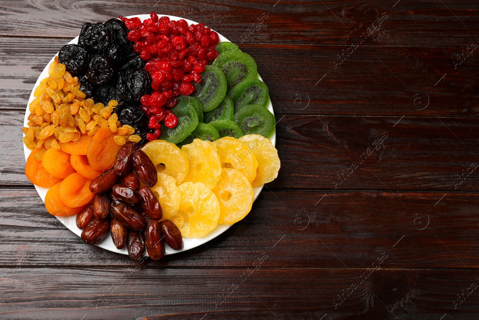 Photo of Mix of different dried fruits on wooden table, top view. Space for text