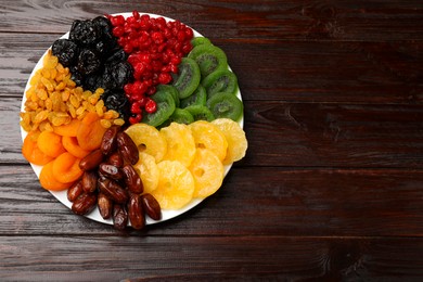 Photo of Mix of different dried fruits on wooden table, top view. Space for text