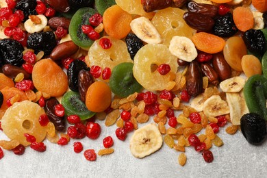 Photo of Mix of different dried fruits on gray textured table, top view