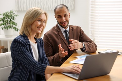 Photo of Coworkers with laptop working together in office