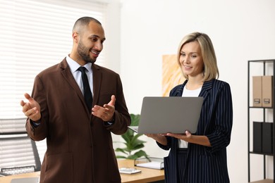 Photo of Coworkers with laptop working together in office