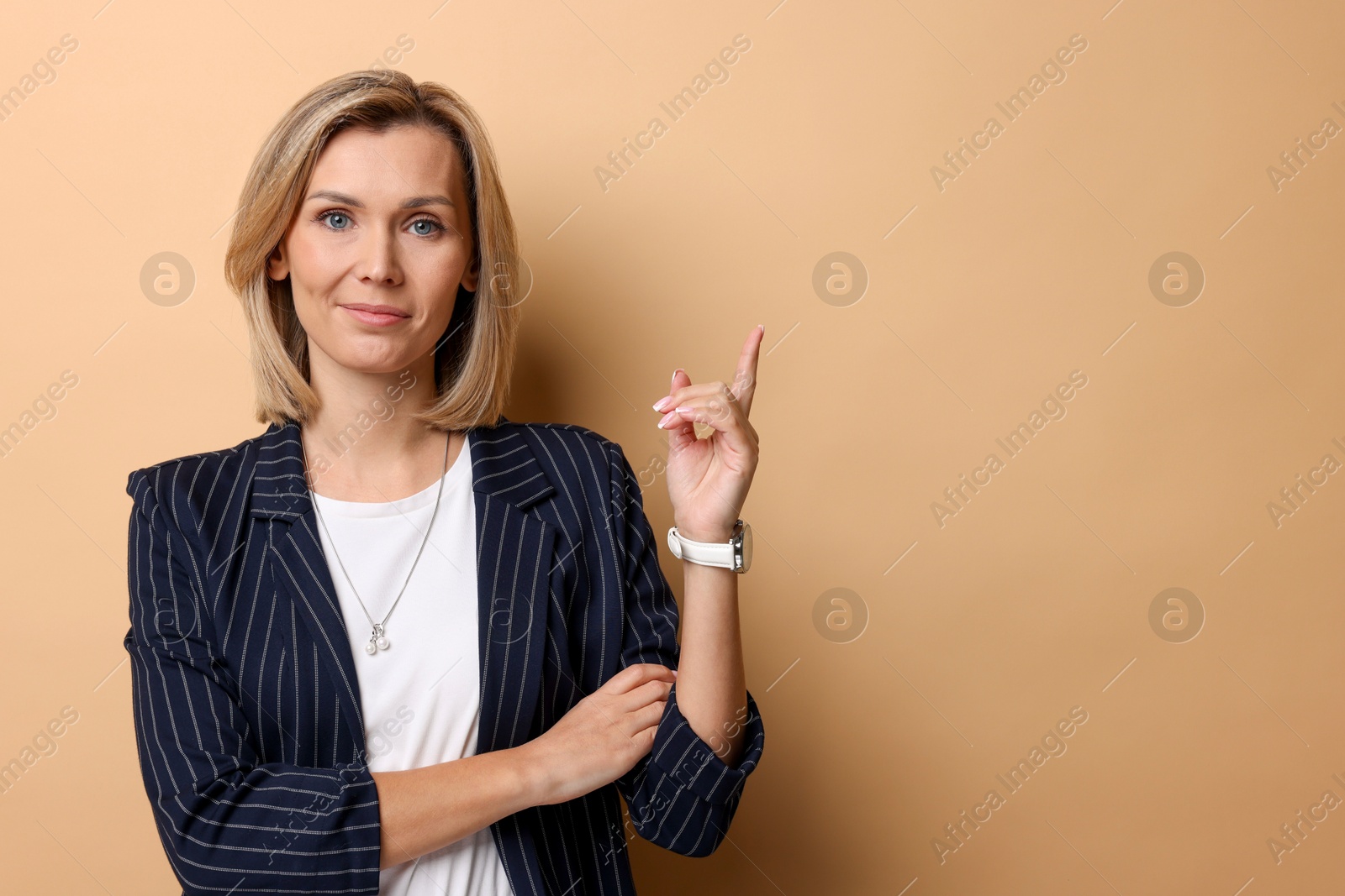 Photo of Portrait of businesswoman pointing at something on beige background, space for text