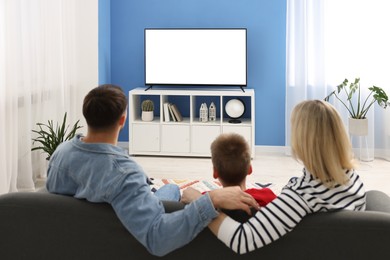 Photo of Happy family watching tv together at home, back view