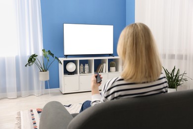 Photo of Woman watching tv on couch at home, back view