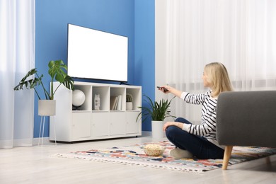 Photo of Woman with popcorn watching tv on floor at home