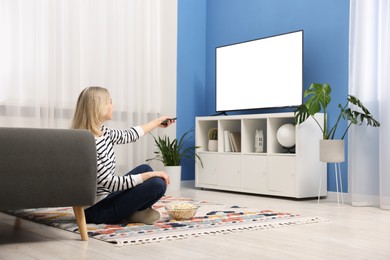 Photo of Woman with popcorn watching tv on floor at home