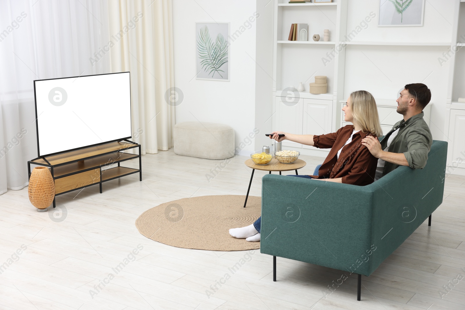 Photo of Lovely couple watching tv on couch at home