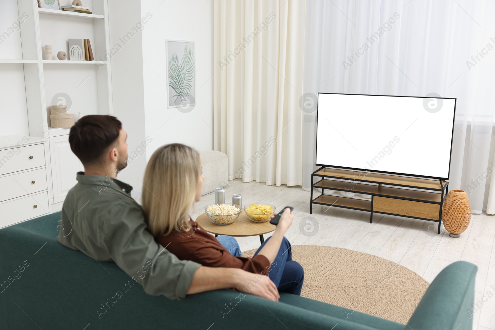 Photo of Lovely couple watching tv on couch at home