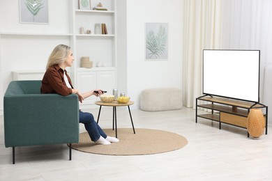 Photo of Woman with snacks and drinks watching tv on couch at home