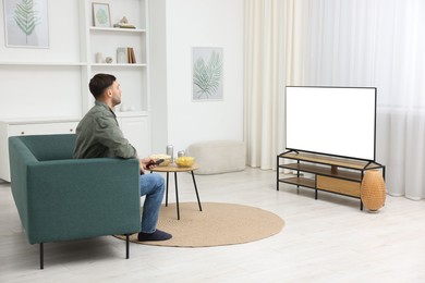 Photo of Man with snacks and drinks watching tv on couch at home