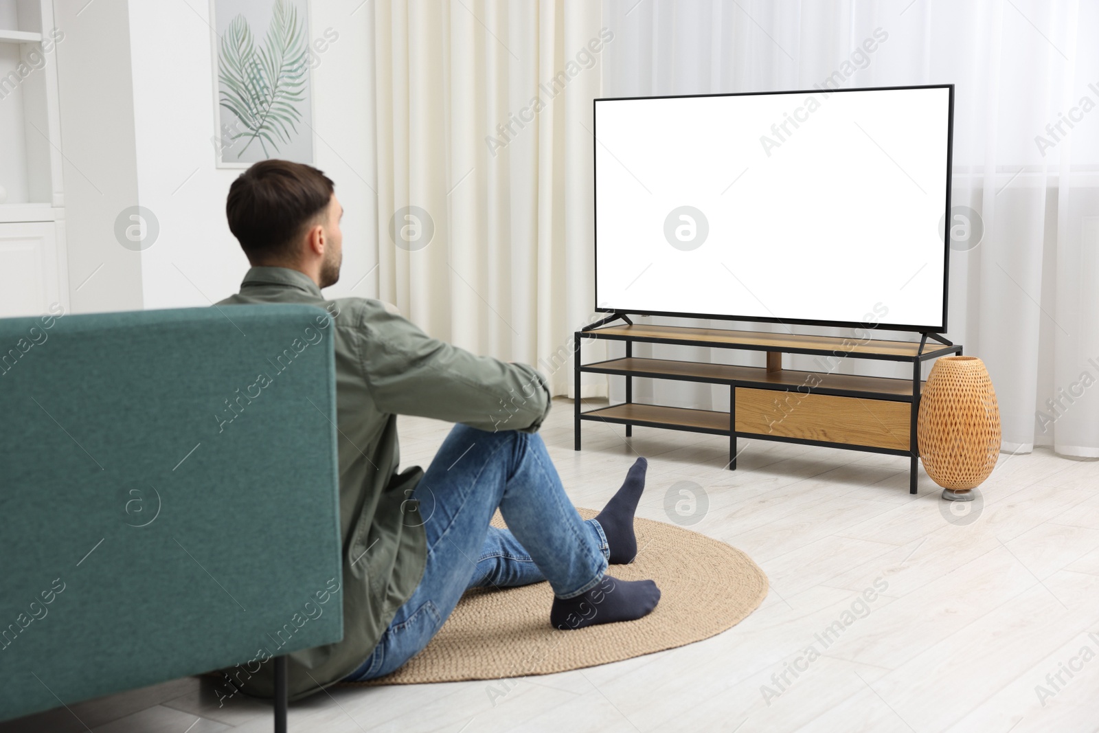 Photo of Man watching tv on floor at home