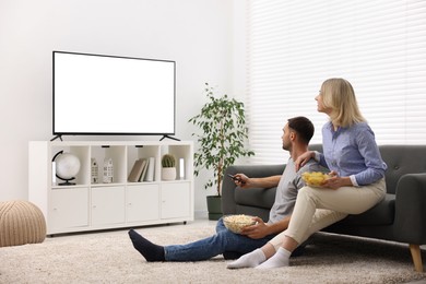 Photo of Lovely couple with snacks watching tv at home