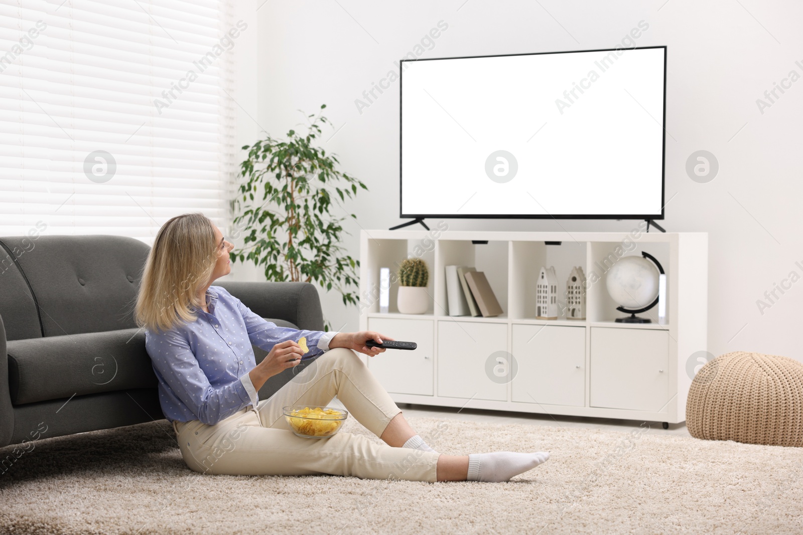 Photo of Woman with chips watching tv at home