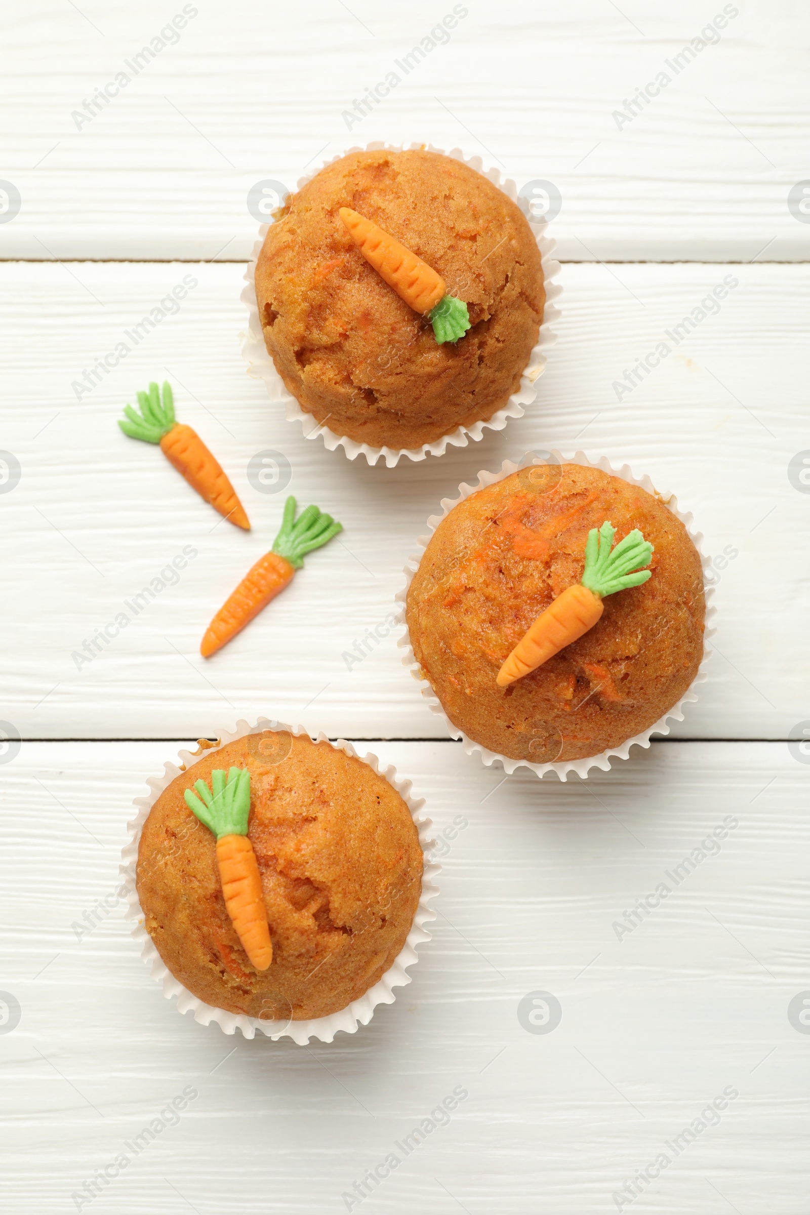 Photo of Tasty carrot muffins on white wooden table, flat lay