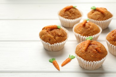 Photo of Tasty carrot muffins on white wooden table, closeup. Space for text