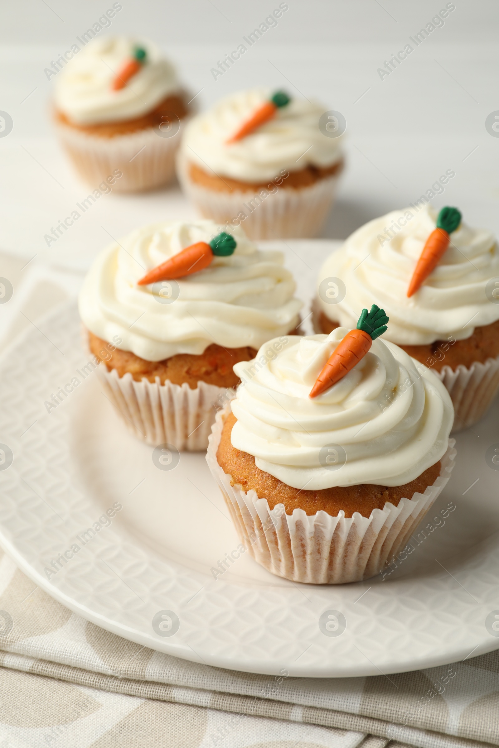 Photo of Tasty carrot muffins with cream on white wooden table, closeup