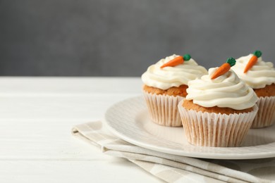 Photo of Tasty carrot muffins with cream on white wooden table, closeup. Space for text