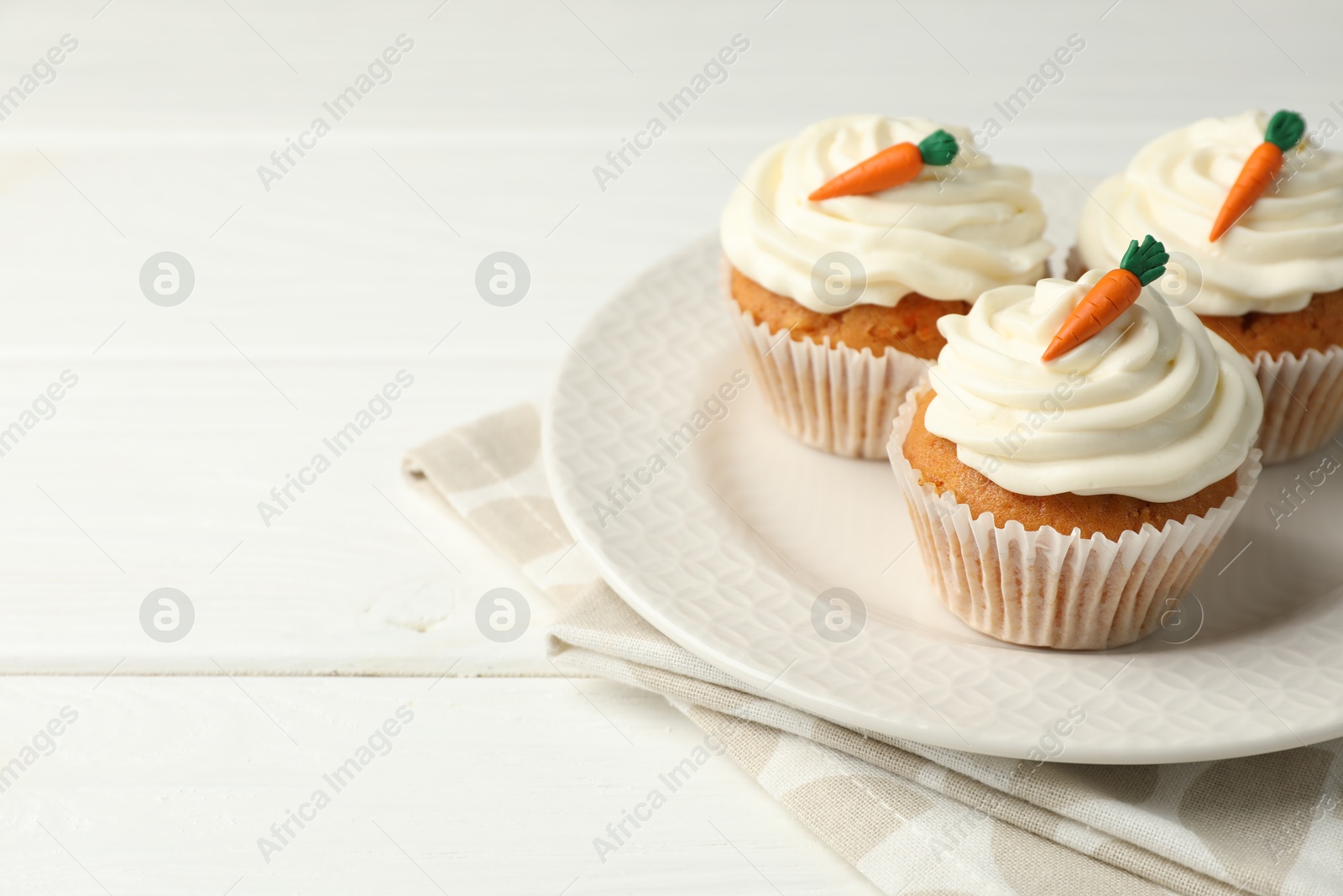 Photo of Tasty carrot muffins with cream on white wooden table, closeup. Space for text