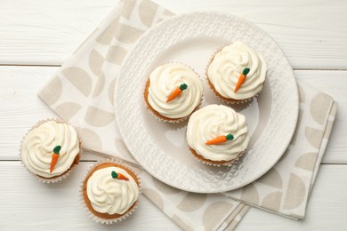 Photo of Tasty carrot muffins with cream on white wooden table, flat lay