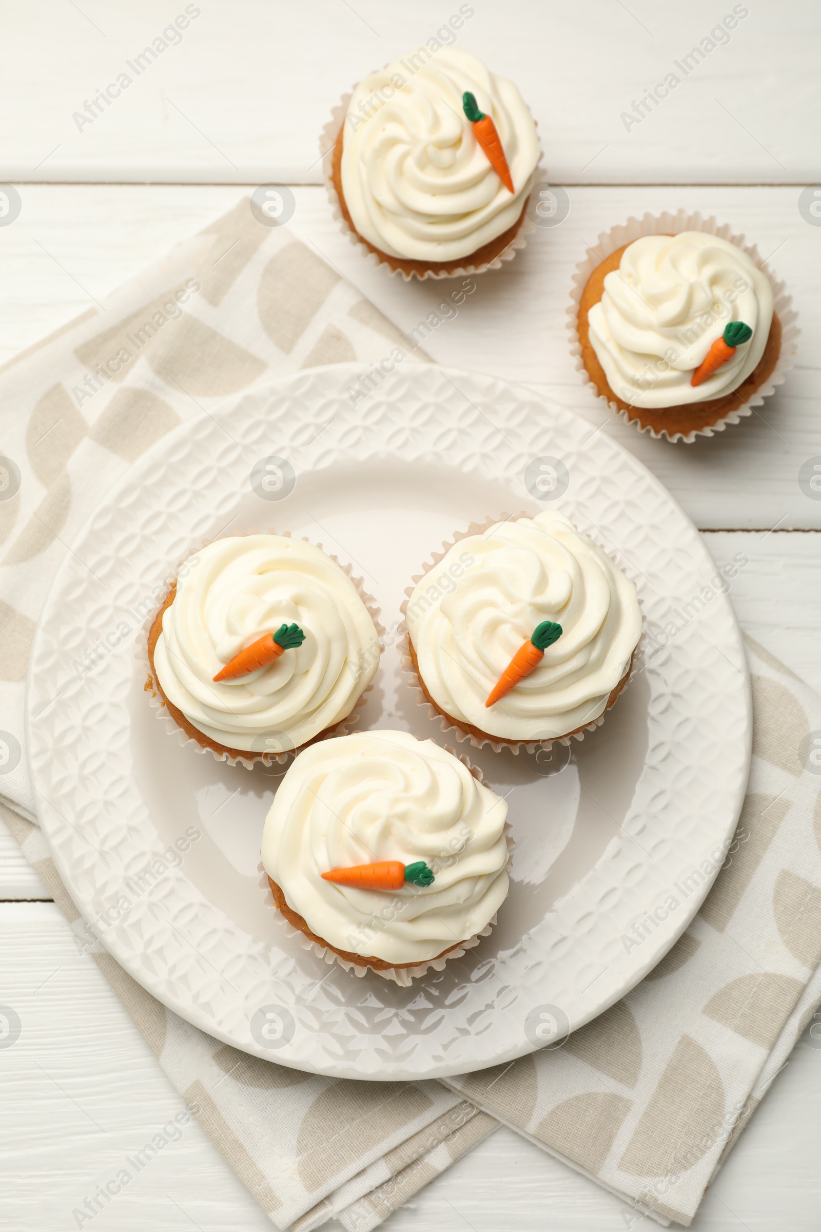 Photo of Tasty carrot muffins with cream on white wooden table, flat lay