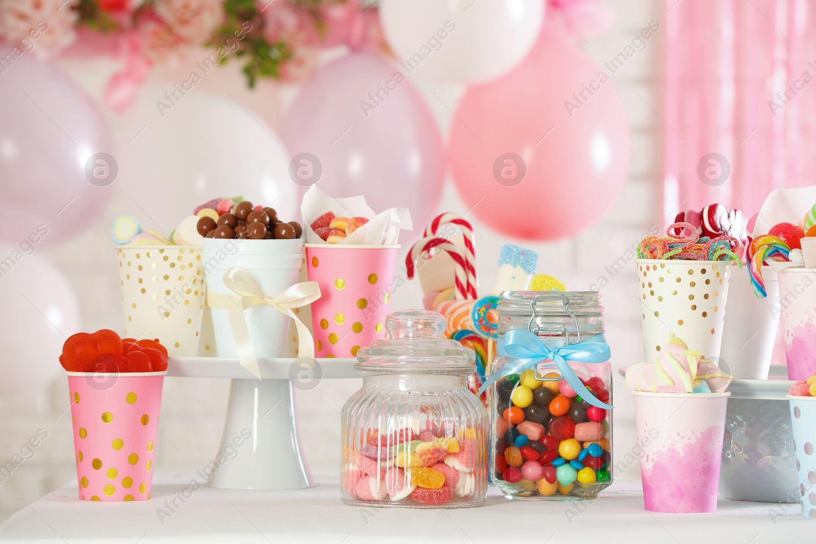 Photo of Candy bar. Many different sweets on table in festive decorated room