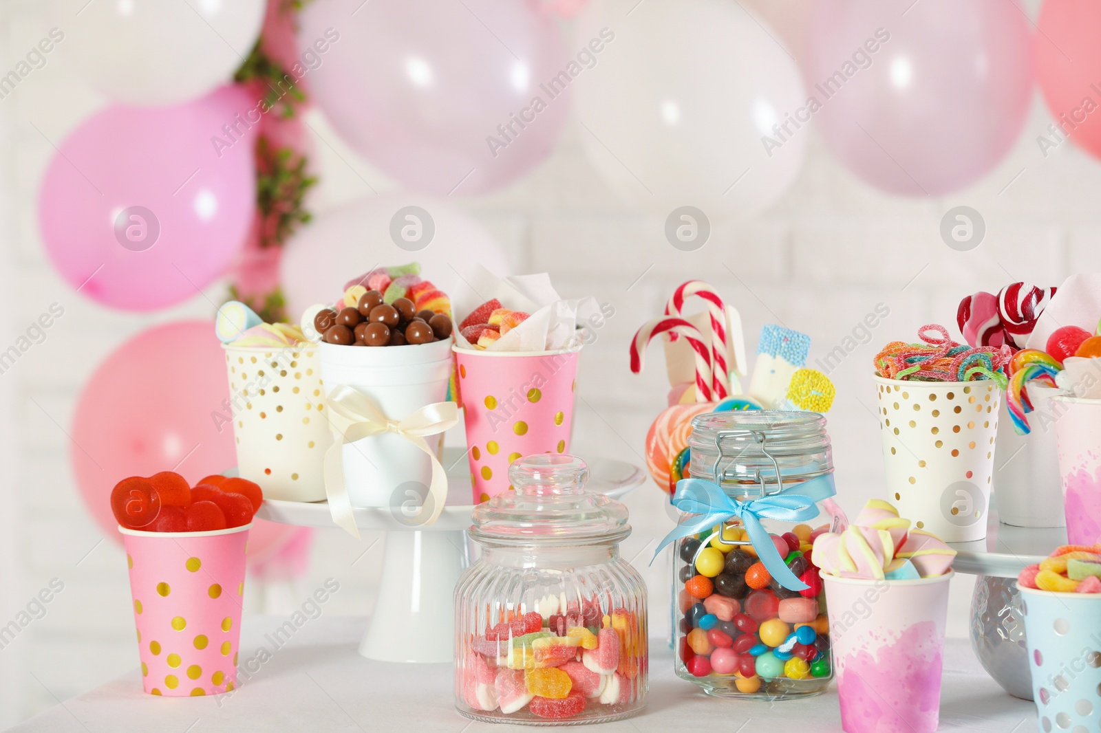 Photo of Candy bar. Many different sweets on table in festive decorated room