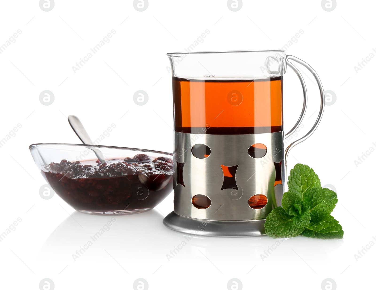 Photo of Glass of aromatic tea in holder, mint and jam isolated on white